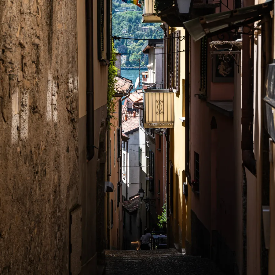 Narrow alley in Bellagio with cobblestone path, traditional houses and a glimpse of the lake