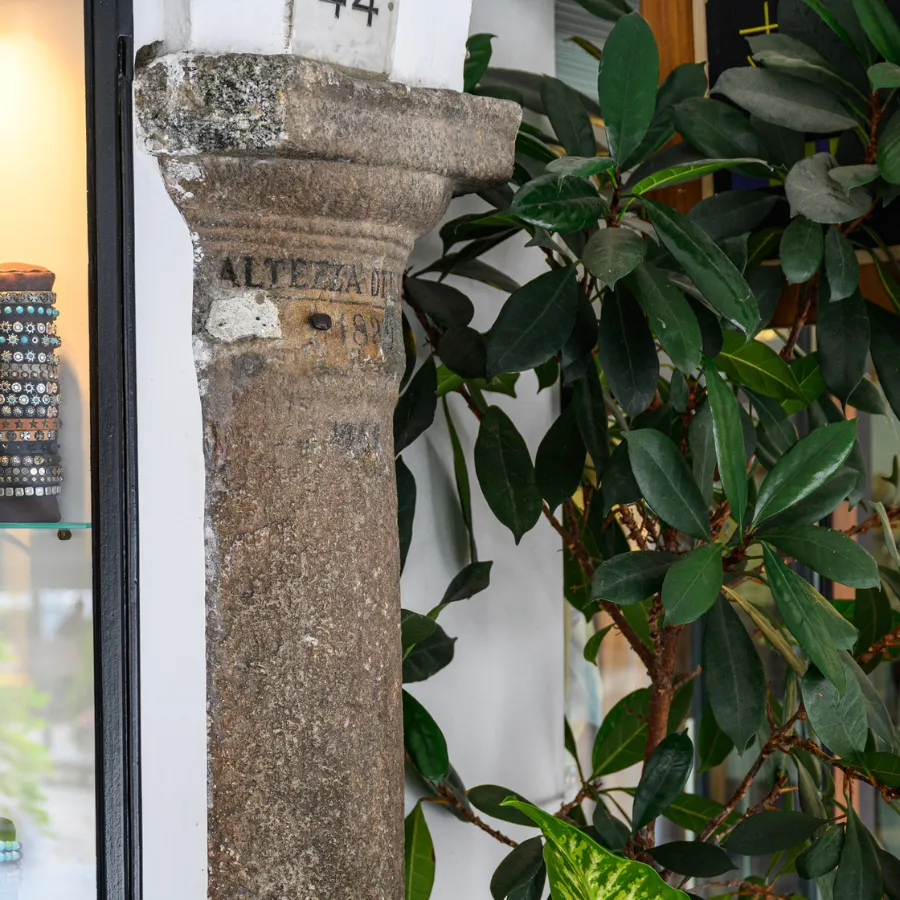 Old stone column with historical flood level mark, next to a shop window in Bellagio