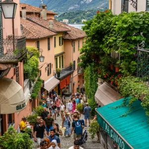 Crowds walking up Salita Serbelloni, a picturesque staircase lined with colorful buildings in Bellagio