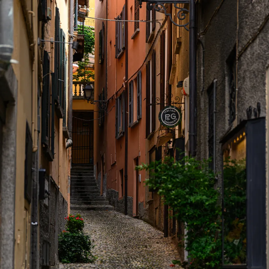 Narrow cobblestone alley in Bellagio with colorful facades and a staircase leading upward
