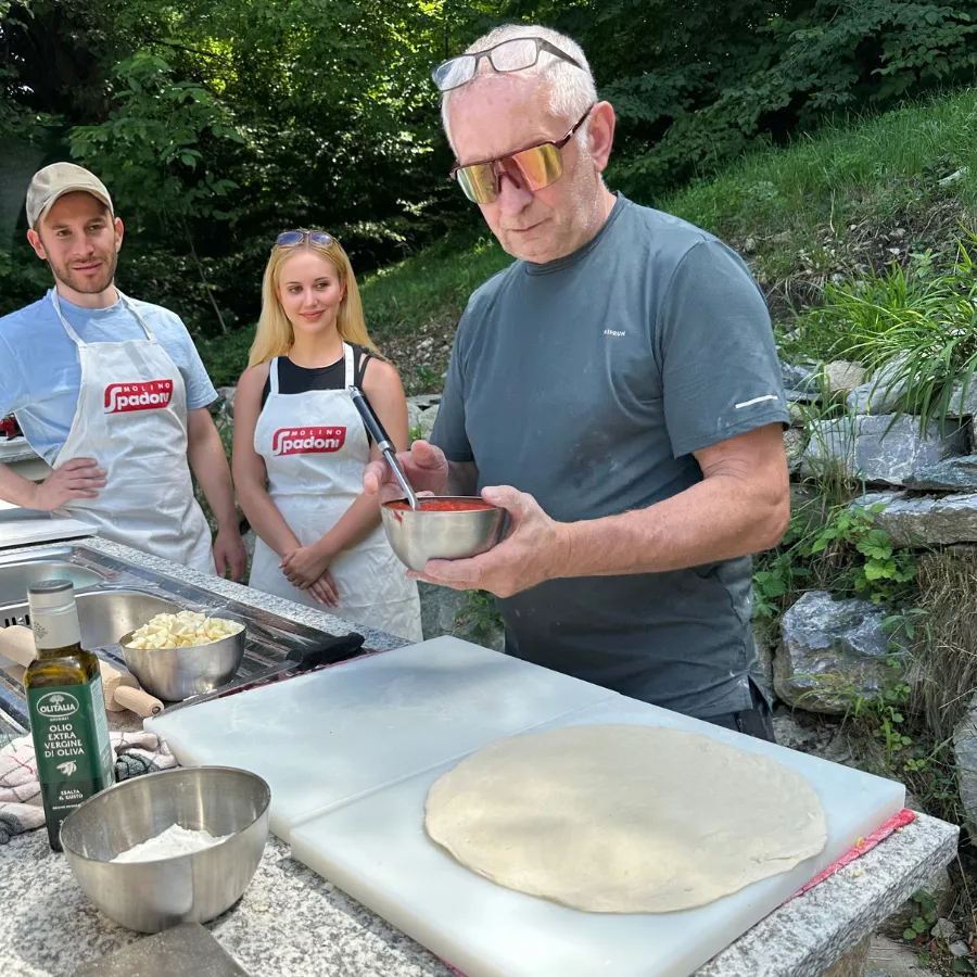 Local chef preparing tomato sauce for pizza during an outdoor cooking lesson on Lake Como