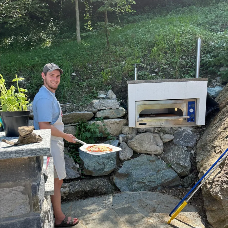 Tourist about to bake a handmade pizza in a wood-fired oven during a cooking class on Lake Como